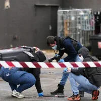 Des policiers examinant des éléments de preuve sur les lieux d'une station-service où un homme a ouvert le feu depuis sa voiture, tuant une personne et en blessant quatre autres selon des sources policières, à Trappes, en banlieue parisienne, le 23 octobre 2026. (Crédit : Dimitar Dilkoff/AFP)