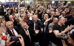 Yousef Jabareen, chef de file de l’alliance politique « Liste arabe unie » (au centre à gauche), et d’autres membres célèbrent les premiers résultats des sondages à la sortie des urnes, diffusés à la télévision au siège de campagne de l’alliance, à Nazareth, le 27 octobre 2026. (Crédit : Ahmad Gharabli/AFP)