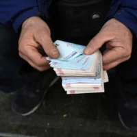 Un cambiste de rue posant pour une photo sans montrer son visage alors qu’il compte des billets de banque iraniens dans un quartier commerçant du centre-ville de Téhéran, en Iran, le 23 décembre 2022. (Crédit : Vahid Salemi/AP)