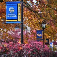 Feuillage d'automne encadrant des bannières sur le campus de l'université de Pittsburgh, le 10 novembre 2025. (AP Photo/Gene J. Puskar)