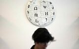 Un contributeur bénévole de Wikipédia sous le logo de Wikipédia, dans les locaux de la Fondation Wikimedia, à San Francisco, en Californie, le 12 janvier 2026. (Crédit : AP Photo/Jeff Chiu)