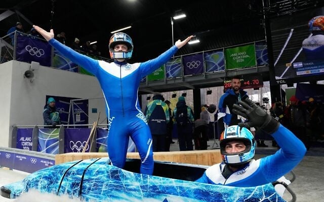 Les Israéliens Adam Edelman, à gauche, et Menachem Chen célèbrent leur performance à l'issue d'une descente de bobsleigh à deux lors des Jeux olympiques d'hiver de 2026, à Cortina d'Ampezzo, en Italie, le 16 février 2026. (AP Photo/Alessandra Tarantino)