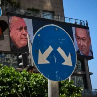 Un homme passe devant un panneau publicitaire numérique d’une chaîne de télévision sur lequel figurent le Premier ministre Benjamin Netanyahu, à droite, et son principal adversaire, le candidat de l’opposition Gadi Eisenkot, à l’approche des élections législatives israéliennes, à Ramat Gan, le 23 septembre 2026. (Crédit : Oded Balilty/AP)