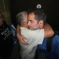 Asaf Rajuan, l’un des passagers israéliens qui est intervenu lors d’une attaque terroriste perpétrée par le copilote contre le pilote, lequel cherchait à faire s’écraser leur vol flydubai, embrasse un autre passager du même vol, à leur arrivée à l’aéroport international Ben Gurion, près de Tel Aviv, en Israël, le 30 septembre 2026. (Crédit: AP/Ariel Schalit)