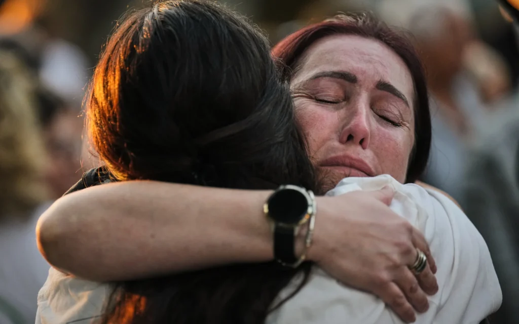 Des personnes assistant à une cérémonie commémorative marquant le troisième anniversaire du pogrom perpétré par le groupe terroriste palestinien du Hamas le 7 octobre 2023, au kibboutz de Kfar Aza, dans le sud d'Israël, où de nombreux membres de la communauté ont été tués et enlevés, le 7 octobre 2026. (Crédit : Ariel Schalit/AP Photo)