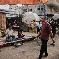 Des Palestiniens se promènent dans un marché du camp de réfugiés d’Al-Shati, à Gaza-City, le 14 octobre 2026. (Crédit : Abdel Kareem Hana/AP)