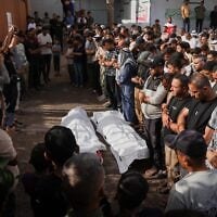 Des personnes en deuil récitent des prières funéraires pour deux Palestiniens tués lors d'une frappe israélienne visant un véhicule, à l'hôpital Nasser de Khan Younès, dans le sud de la bande de Gaza, le 15 octobre 2026. (Crédit : AP Photo/Abdel Kareem Hana)