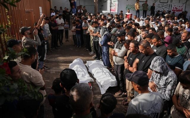 Des personnes en deuil récitent des prières funéraires pour deux Palestiniens tués lors d'une frappe israélienne visant un véhicule, à l'hôpital Nasser de Khan Younès, dans le sud de la bande de Gaza, le 15 octobre 2026. (Crédit : AP Photo/Abdel Kareem Hana)