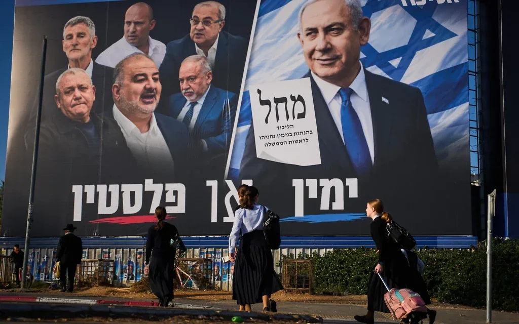 Des passants devant une affiche électorale du Likud montrant le Premier ministre Benjamin Netanyahu aux côtés de dirigeants de partis d’opposition, accompagnée du slogan en hébreu « La droite ou la Palestine », à Bnei Brak, en Israël, le 18 octobre 2026. (Crédit : Oded Balilty/AP) Des passants devant une affiche électorale du Likud montrant le Premier ministre Benjamin Netanyahu aux côtés de dirigeants de partis d’opposition, accompagnée du slogan en hébreu « La droite ou la Palestine », à Bnei Brak, en Israël, le 18 octobre 2026. (Crédit : Oded Balilty/AP)