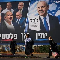 Des passants devant une affiche électorale du Likud montrant le Premier ministre Benjamin Netanyahu aux côtés de dirigeants de partis d’opposition, accompagnée du slogan en hébreu « La droite ou la Palestine », à Bnei Brak, en Israël, le 18 octobre 2026. (Crédit : Oded Balilty/AP)