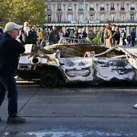 Des passants observant une voiture calcinée sur la place de la République, au lendemain d'une manifestation en solidarité avec les revendications des étudiants, à Paris, le 18 octobre 2026. (Crédit : Emma Da Silva/AP)