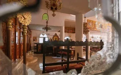 L'intérieur d'une église grecque-orthodoxe, vu à travers une vitre brisée, quelques heures après que des terroristes armés ont ouvert le feu lors d'un enterrement, dans le village de Hammoud, dans le gouvernorat de Karak, en Jordanie, le 23 octobre 2026. (Crédit : AP Photo)