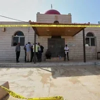 Des agents d’entretien et d’autres personnes rassemblés devant l’église grecque-orthodoxe Saint-Georges, au lendemain de la fusillade perpétrée par des terroristes armés lors d’un enterrement dans le village de Hamoud, dans le gouvernorat de Karak, en Jordanie, le 24 octobre 2026. (Crédit : Raad Adayleh/AP)