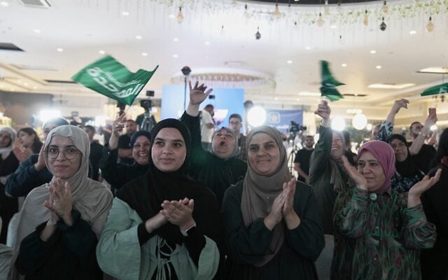 Des partisans du parti Raam, dirigé par le député israélien Mansour Abbas, applaudissent et agitent des drapeaux du parti après la publication des premiers résultats des sondages en sortie des urnes lors des élections législatives israéliennes, à Sakhnin, en Israël, le 27 octobre 2026. (AP Photo/Mahmoud Illean)