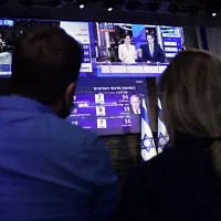 Des militants à Tel Aviv suivent les sondages à la sortie des urnes le soir des élections, le 23 mars 2021. (Crédit : Tomer Neuberg/Flash90)
