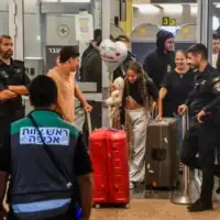 Des passagers du vol FZ1073 de Flydubai marchant avec leurs proches dans le hall des arrivées de l’aéroport Ben Gurion, près de Tel Aviv, sous le regard du personnel de sécurité, après que leur vol initial de Dubaï vers Israël a été dérouté vers l’Arabie saoudite à la suite d’une tentative d'assassinat du pilote par son copilote, le 30 septembre 2026. (Crédit : Avshalom Sassoni/Flash90)