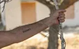 Un résident du kibboutz Beeri montre le tatouage "7.10.2023" sur son bras, en mémoire du pogrom du Hamas du 7-Octobre, au kibboutz Beeri, près de la frontière israélienne avec la bande de Gaza, quelques jours avant le troisième anniversaire de l'attaque, le 4 octobre 2026. (Chaim Goldberg/Flash90)