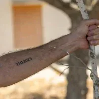 Un résident du kibboutz Beeri montre le tatouage "7.10.2023" sur son bras, en mémoire du pogrom du Hamas du 7-Octobre, au kibboutz Beeri, près de la frontière israélienne avec la bande de Gaza, quelques jours avant le troisième anniversaire de l'attaque, le 4 octobre 2026. (Chaim Goldberg/Flash90)