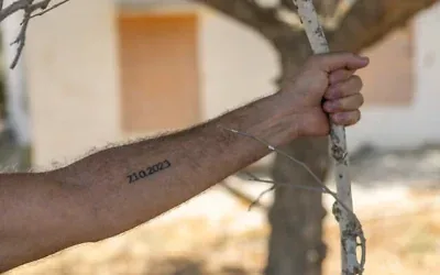 Un résident du kibboutz Beeri montre le tatouage "7.10.2023" sur son bras, en mémoire du pogrom du Hamas du 7-Octobre, au kibboutz Beeri, près de la frontière israélienne avec la bande de Gaza, quelques jours avant le troisième anniversaire de l'attaque, le 4 octobre 2026. (Chaim Goldberg/Flash90)