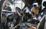 Des Palestiniens inspectant les dégâts après que des résidents d'implantation extrémistes auraient incendié quatre véhicules et tagué des graffitis en hébreu sur les murs des maisons du village palestinien d'Aqraba, au sud de Naplouse en Cisjordanie, le 6 octobre 2026. (Crédit : Nasser Ishtayeh/Flash90)
