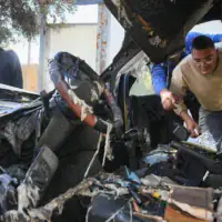 Des Palestiniens inspectant les dégâts après que des résidents d'implantation extrémistes auraient incendié quatre véhicules et tagué des graffitis en hébreu sur les murs des maisons du village palestinien d'Aqraba, au sud de Naplouse en Cisjordanie, le 6 octobre 2026. (Crédit : Nasser Ishtayeh/Flash90)