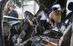 Des Palestiniens inspectant les dégâts après que des résidents d'implantation extrémistes auraient incendié quatre véhicules et tagué des graffitis en hébreu sur les murs des maisons du village palestinien d'Aqraba, au sud de Naplouse en Cisjordanie, le 6 octobre 2026. (Crédit : Nasser Ishtayeh/Flash90)