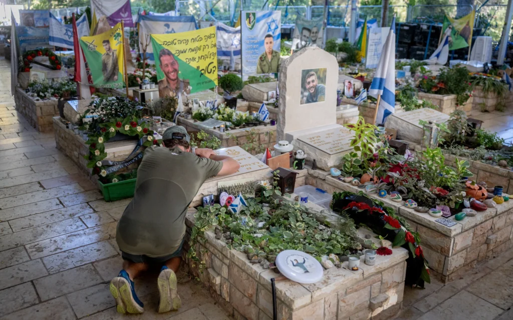 Un homme se recueillant devant une tombe au mont Herzl, dans la section réservée aux victimes du pogrom perpétré par le groupe terroriste palestinien du Hamas le 7 octobre 2023, le 7 octobre 2026. (Crédit : Chaïm Goldberg/FLASH90)