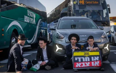 Des Haredim bloquant la circulation lors d'une manifestation contre l'enrôlement à Jérusalem, le 8 octobre 2026. Les deux manifestants à droite tiennent une pancarte sur laquelle on peut lire : « Haredi ou armée ». (Crédit : Chaïm Goldberg/Flash90)