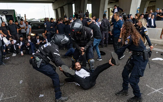 Des manifestants ultra-orthodoxes se sont affrontés avec des policiers et des civils alors qu'ils bloquaient la Route 4 lors d'une manifestation contre l'incarcération d'étudiants de yeshivot qui n'avaient pas respecté un ordre de conscription de l'armée, à l'échangeur de Yavne, le 18 octobre 2026. (Crédit : Chaïm Goldberg/Flash90) Des manifestants ultra-orthodoxes se sont affrontés avec des policiers et des civils alors qu'ils bloquaient la Route 4 lors d'une manifestation contre l'incarcération d'étudiants de yeshivot qui n'avaient pas respecté un ordre de conscription de l'armée, à l'échangeur de Yavne, le 18 octobre 2026. (Crédit : Chaïm Goldberg/Flash90)