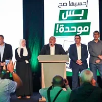 Le chef du parti Raam, Mansour Abbas, et d’autres membres du parti se tenant sur scène après la publication des résultats des sondages à la sortie des urnes, à Sakhnin, le 27 octobre 2026. (Crédit : Michael Giladi/Flash90)
