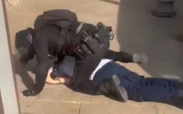Capture d’écran d’une vidéo diffusée sur les réseaux sociaux, un policier immobilise au sol un chauffeur de bus arabe sur un trottoir de Jérusalem, le 22 octobre 2026. (Crédit : Ahmad Tibi/X)