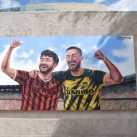 Une fresque murale de l’artiste Tomer Peretz, représentant Hersh Goldberg-Polin (à gauche) et Ori Danino (à droite) dans les maillots de leurs équipes respectives, a été dévoilée au stade Teddy de Jérusalem par la municipalité le 5 octobre 2026. (Crédit : Autorisation)