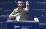 Ofer Winter déchire ce qu'il présente comme un exemplaire des Accords d'Oslo lors de la conférence de l'ICT organisée à l'université Reichman, le 8 octobre 2026 (Crédit : Amkha Yisrael)
