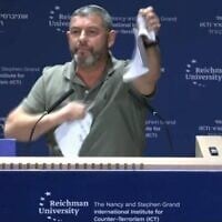Ofer Winter déchire ce qu'il présente comme un exemplaire des Accords d'Oslo lors de la conférence de l'ICT organisée à l'université Reichman, le 8 octobre 2026 (Crédit : Amkha Yisrael)