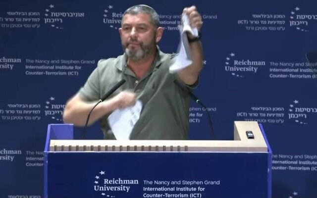Ofer Winter déchire ce qu'il présente comme un exemplaire des Accords d'Oslo lors de la conférence de l'ICT organisée à l'université Reichman, le 8 octobre 2026 (Crédit : Amkha Yisrael)
