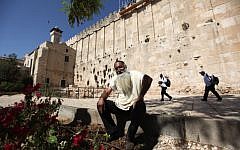 A Jewish settler sits outside the Tomb of the Patriarchs in the West Bank city of Hebron (photo credit: Kobi Gideon/Flash90)