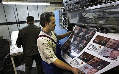 Printed posters of Mostafa Kavakebian, a candidate in the upcoming election, in a printing house in Tehran (photo credit: AP/Vahid Salemi)