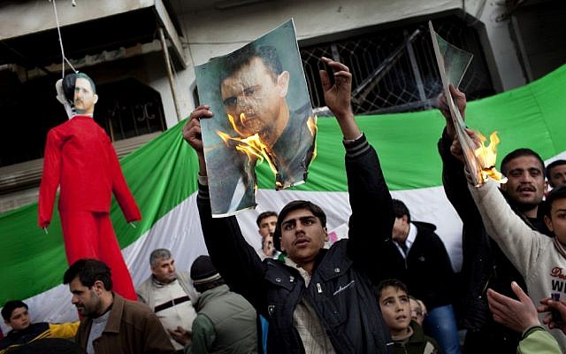 Protestors burn portraits of Syrian President Bashar Assad during an anti-government demonstration (photo credit: AP/Rodrigo Abd) Protestors burn portraits of Syrian President Bashar Assad during an anti-government demonstration (photo credit: AP/Rodrigo Abd)
