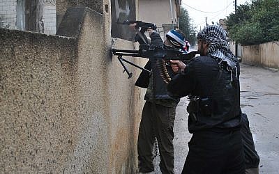 Syrian rebels take their position behind a wall as they fire their guns during a battle with the Syrian government forces, at Rastan area in Homs province, central Syria, on Tuesday Jan. 31, 2012. (photo credit: AP)  