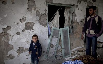 Residents stand by their house destroyed in clashes between the Free Syrian Army and President Assad's forces in Sarmin, north of Syria, on Tuesday. (photo credit: AP/Rodrigo Abd)
