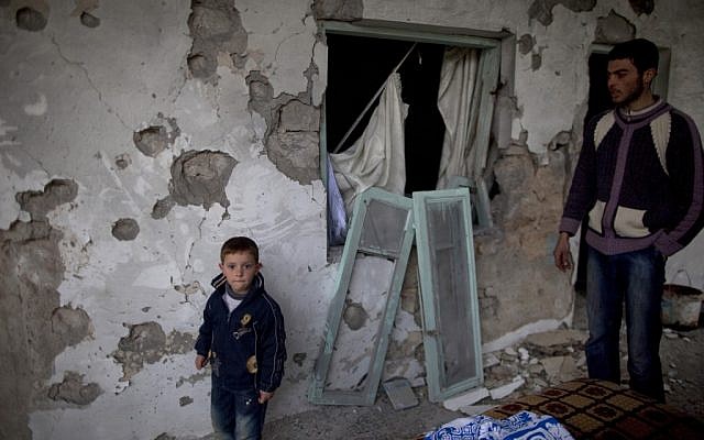 Residents stand by their house destroyed in clashes between the Free Syrian Army and President Assad's forces in Sarmin, north of Syria, on Tuesday. (photo credit: AP/Rodrigo Abd) Residents stand by their house destroyed in clashes between the Free Syrian Army and President Assad's forces in Sarmin, north of Syria, on Tuesday. (photo credit: AP/Rodrigo Abd)