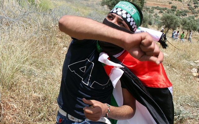A Palestinian protester throwing a stone at a protest in Bilin. (Illustrative photo; credit: Issam Rimawi/Flash90)