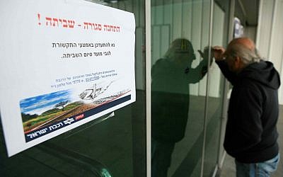 A man looks through the window of a deserted Tel Aviv train station. The sign reads "The station is closed - Strike!" (photo credit: Yehoshua Yosef/Flash90)