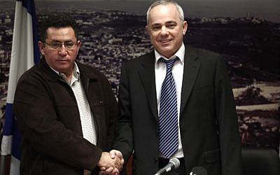A stern looking Histadrut Chairman Ofer Eini shakes hands with smiling Finance Minister Yuval Steinitz during a joint press conference Sunday morning after all-night negotiations that ended the general strike (photo credit: Uri Lenz/Flash90)