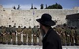 An ultra-Orthodox man observes a group of soldiers at the Western Wall in Jerusalem (illustrative photo: Yonatan Sindel/Flash90)