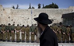 An ultra-Orthodox man observes a group of soldiers at the Western Wall in Jerusalem (illustrative photo: Yonatan Sindel/Flash90)