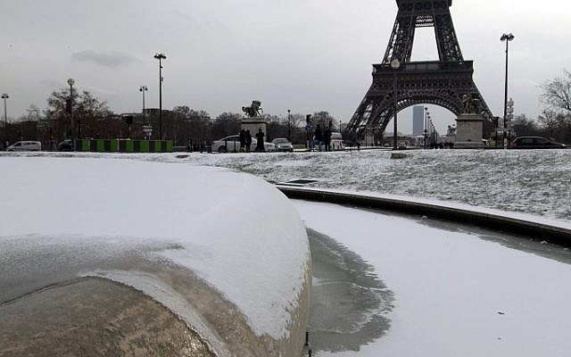 People look at the snow at the Trocadero near the Eiffel Tower seen in background, in Paris, Sunday Feb. 5, 2012.  (photo credit: AP/Jacques Brinon)