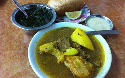 Marak Teimani, aka Yemeni Soup, served hot and spicy, with schug (left) and hilbeh (right) and a loaf of bread with lemon (photo credit: Michal Shmulovich/Times of Israel)