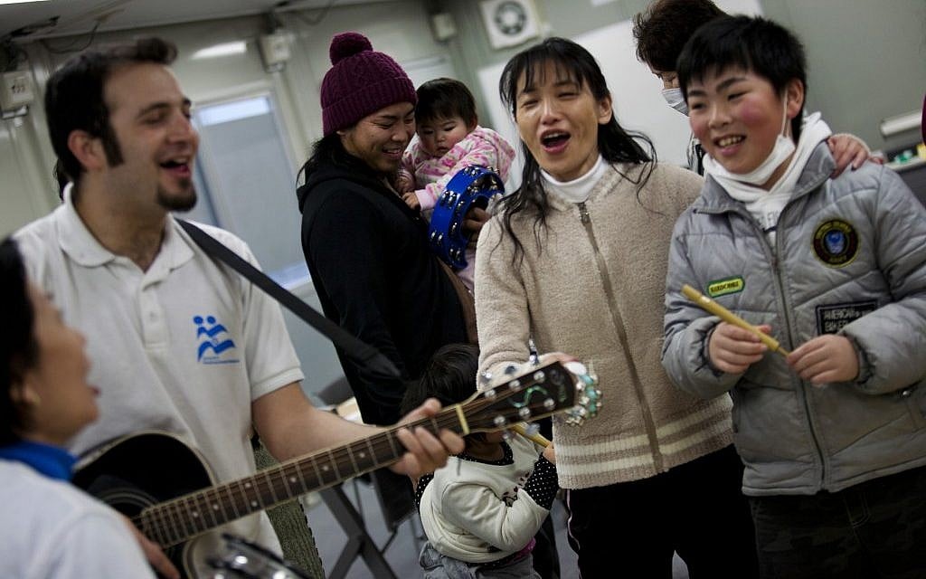 Yotam Polizer, IsraAID's Japan project manager, plays guitar for residents of a temporary housing site for tsunami survivors in Ishinomaki as part of a music therapy session (photo credit: Boaz Arad/JTA) Yotam Polizer, IsraAID's Japan project manager, plays guitar for residents of a temporary housing site for tsunami survivors in Ishinomaki as part of a music therapy session (photo credit: Boaz Arad/JTA)