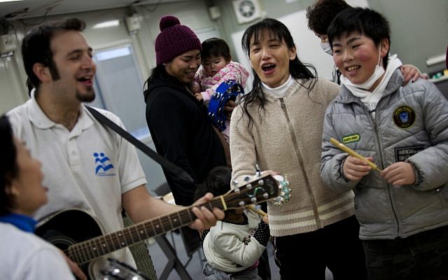 Yotam Polizer, IsraAID's Japan project manager, plays guitar for residents of a temporary housing site for tsunami survivors in Ishinomaki as part of a music therapy session (photo credit: Boaz Arad/JTA)